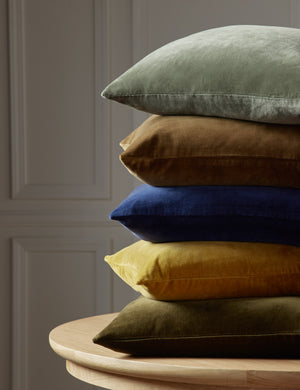 Charlotte velvet pillow in shale blue, toast, true blue, mustard, and olive green are stacked atop each other