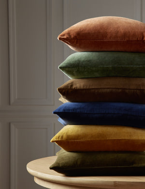 Charlotte velvet pillow in olive green, mustard, true blue, toast, moss, and burnt orange are stacked atop each other