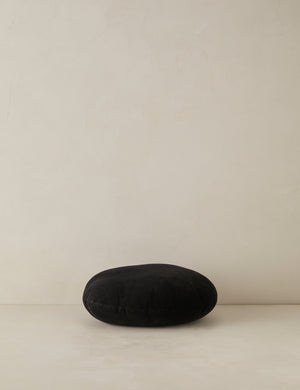 Velvet round accent pillow in black laying flat