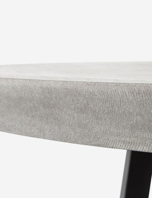 Close-up view of the side of the tabletop on the Agatha indoor and outdoor dining table with lavastone top and black iron base