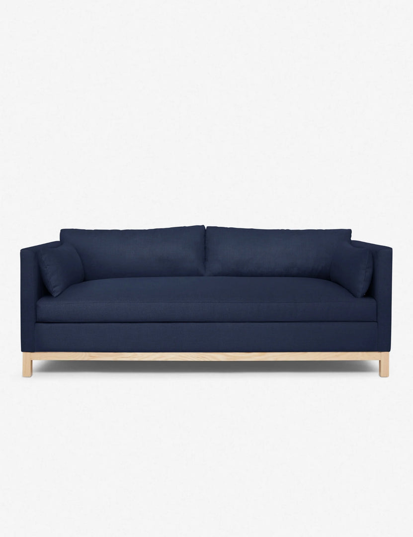 Side view of olive-green velvet sofa showing arm and wooden base.
