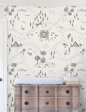 The Through the Woods Wallpaper is in a room with a six drawer distressed wooden dresser with a changing station atop it