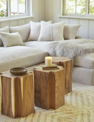 Three Lolani plus shaped wooden side tables sit in a warm living room with a linen sectional, a gray plush sheepskin throw, and a white chevron patterned rug.