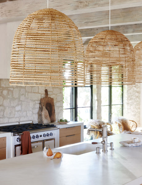 #color::natural | Three Beehive jute woven pendant lights are hung above a kitchen island in a kitchen with stone walls