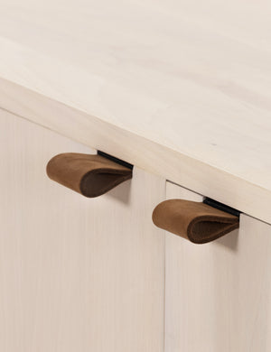 Close-up of the brown leather pulls on the Rosamonde natural wood sideboard