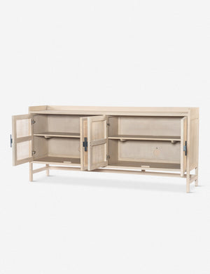 Angled view of the Philene natural mango wood sideboard with cane doors with all four doors open, revealing the inner shelving