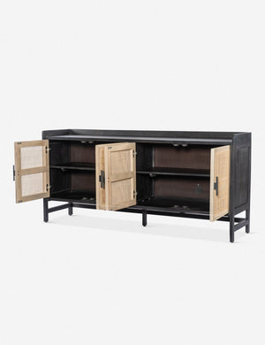 Angled view of the Philene black mango wood sideboard with cane doors with all four doors open, revealing its inner shelving