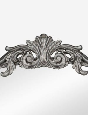 Detailed view of the traditional scroll detailing on the top of the Tulca silver curved standing mirror with flat bottom edge.
