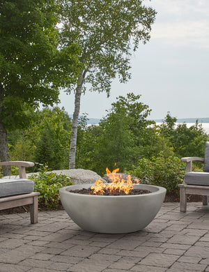 The Benno shade fire bowl sits in an outdoor space next to outdoor lounge furniture