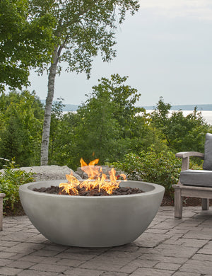 The Benno shade fire bowl sits in an outdoor space next to outdoor lounge furniture