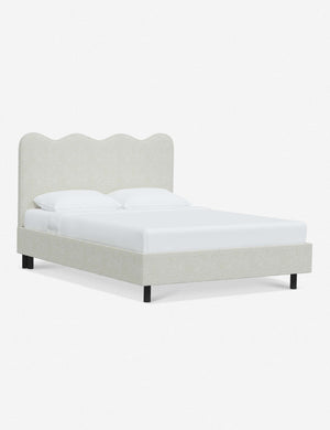 Angled view of Clementine white boucle platform bed with undulating lined headboard