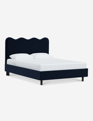 Angled view of Clementine navy velvet platform bed with undulating lined headboard