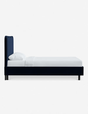 Side view of Clementine navy velvet platform bed with undulating lined headboard