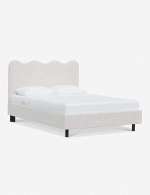 Angled view of Clementine snow velvet platform bed with undulating lined headboard
