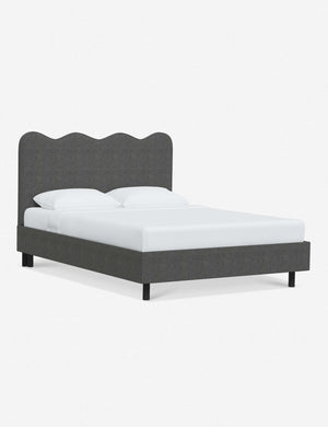 Angled view of Clementine charcoal linen platform bed with undulating lined headboard