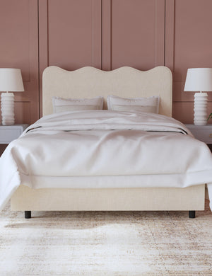 Clementine talc linen platform bed with undulating lined headboard sits in a bedroom with dusty pink accented walls between two ribbed lamps