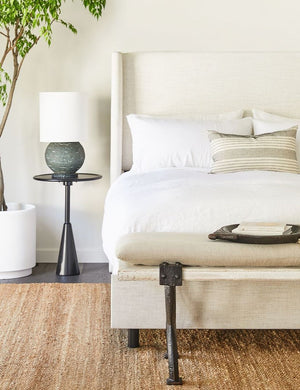 The Set of two european flax linen white pillowcases by cultiver sit on a natural linen framed adara bed in a bedroom with a jute rug and a shiny black nightstand