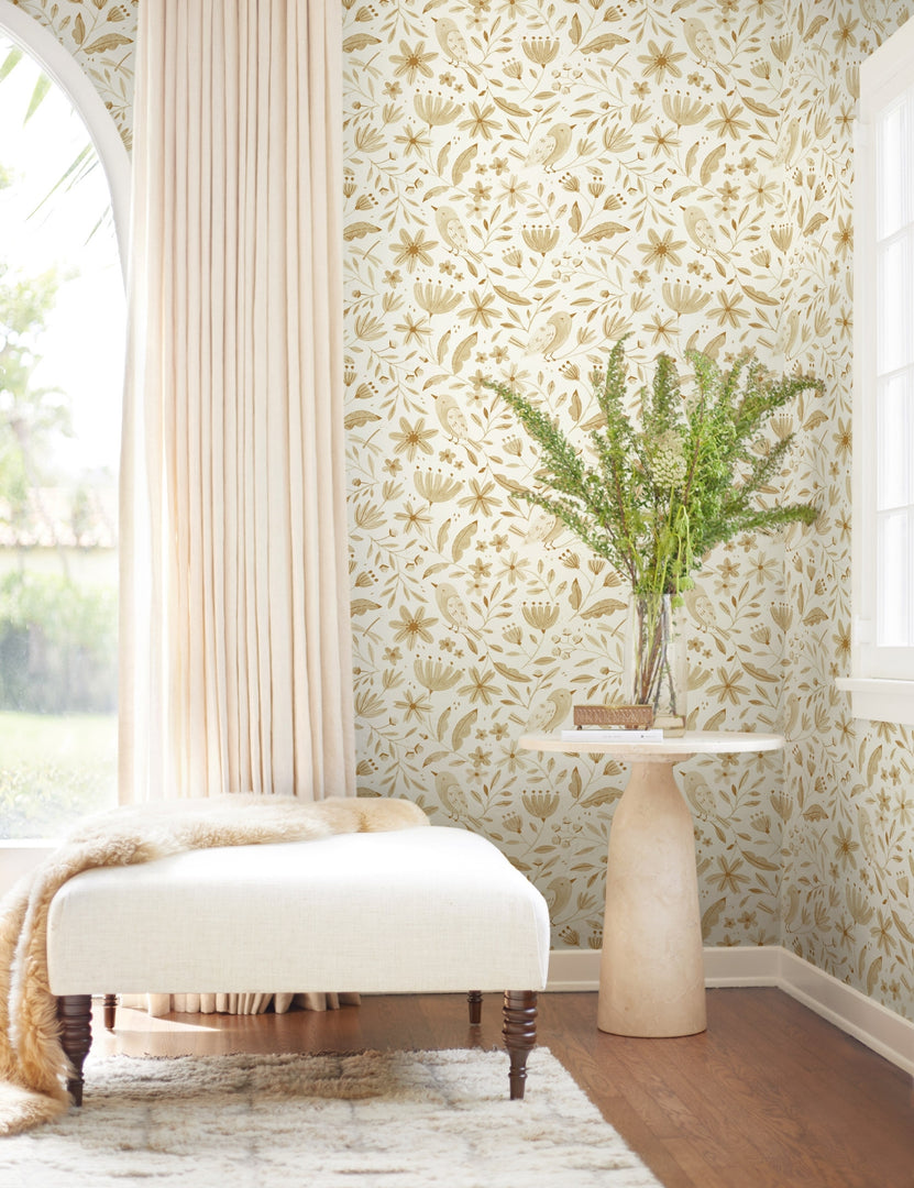 | The Garden Birds Wallpaper is in a room with sheer pink curtains, a white linen ottoman, and an ivory stone round side table