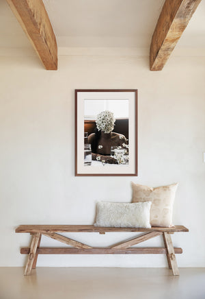 The Southern Woman in White Dogwoods Photography Print in a walnut frame hangs above a wooden bench with two throw pillows