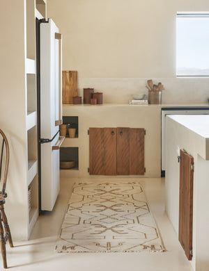 The Evet neutral geometric wool floor rug lays in a neutral kitchen with stone counters.