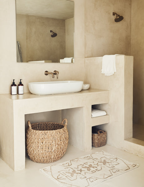 #size::2--x-3- | The Evet neutral geometric wool floor mat lays in a stone bathroom in front of a stone vanity with basin sink.