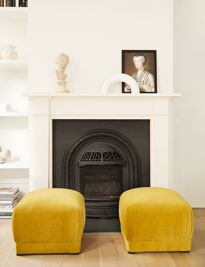 #color::citronella-velvet | Two Bailee citronella velvet ottomans sit in a white living room in front of a fire place