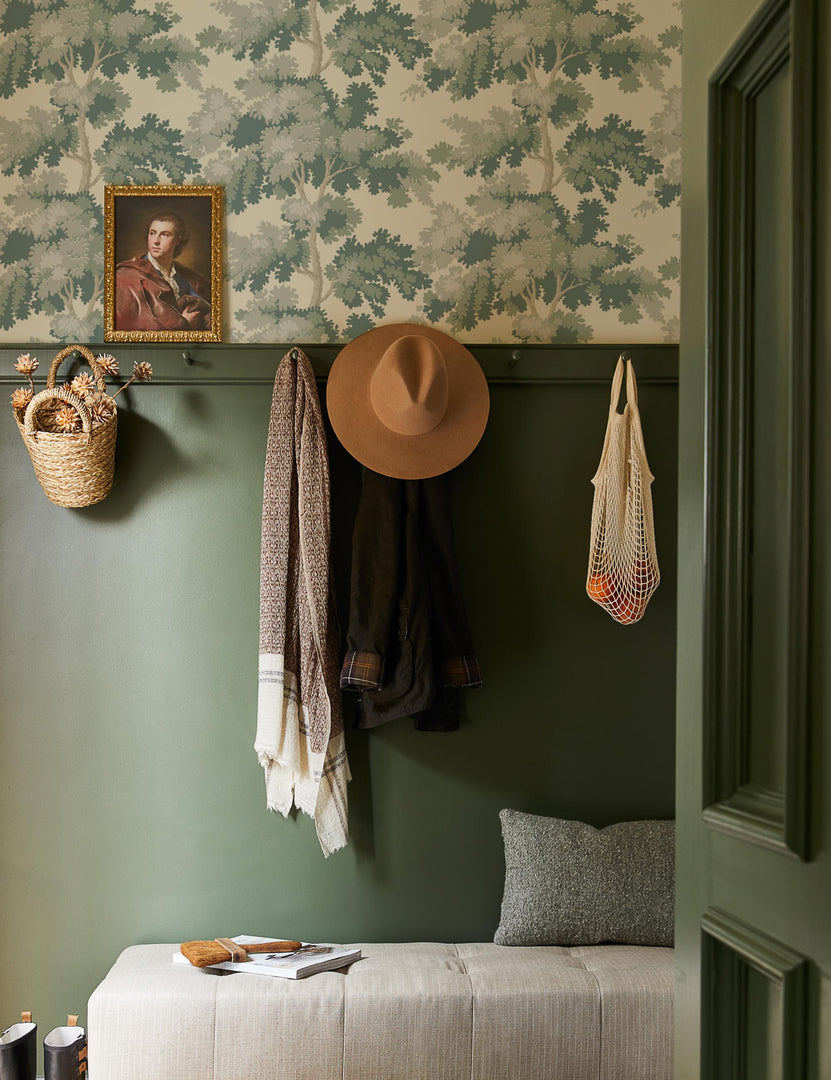 #color::green | The Scalamandre botanical inspired green raphael wallpaper is in an entry way with green accented walls and a gray linen cushioned bench