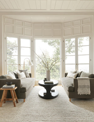 Two Loden Gray Velvet Belmont Sofas sit opposite each other with an oval coffee table in between them in a room with floor to ceiling French doors