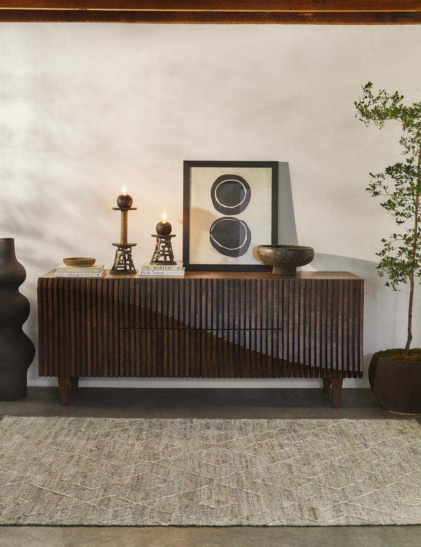 #color::matte-Black | The Lemieux et Cie Pasteur matte black geometric curved Floor Vase sits in a room with a wooden textured sideboard, a textured brown carpet, and a geometric wall art