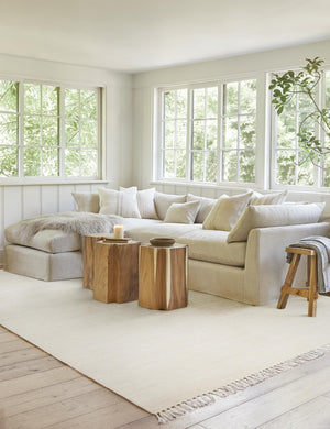 The Sierra Rug lays in a living room under three plus-shaped side tables and a natural linen sectional sofa