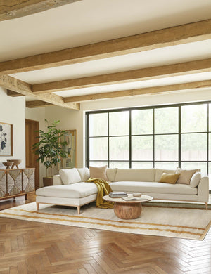 The Charleston ivory left-facing sectional sofa sits in a neutral-toned living room with a plush ivory rug