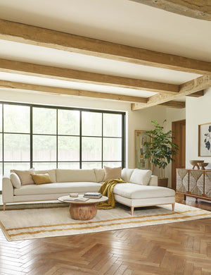 The Charleston ivory right-facing sectional sofa sits in a neutral-toned living room atop a plush ivory rug