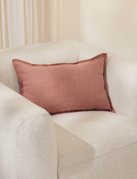 #color::terracotta #style::lumbar | The arlo Terracotta lumbar pillow sits in a studio on a white linen accent chair
