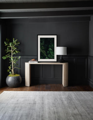 The Still Life 14 Photography Print sits on a whitewashed sideboard next to a lamp in a room with black walls and a gray rug