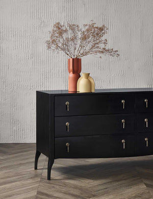The Anabella black wood dresser with silver drawer pulls sits in a room with orange and yellow sculptural vases sitting atop it.