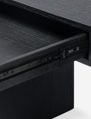 Close up of the drawer of the Mags sculptural solid wood desk in black.