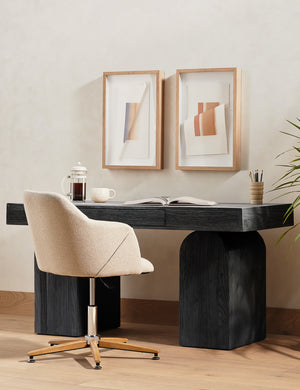 Mags sculptural solid wood desk in black paired with an upholstered desk chair and set of wall artwork.