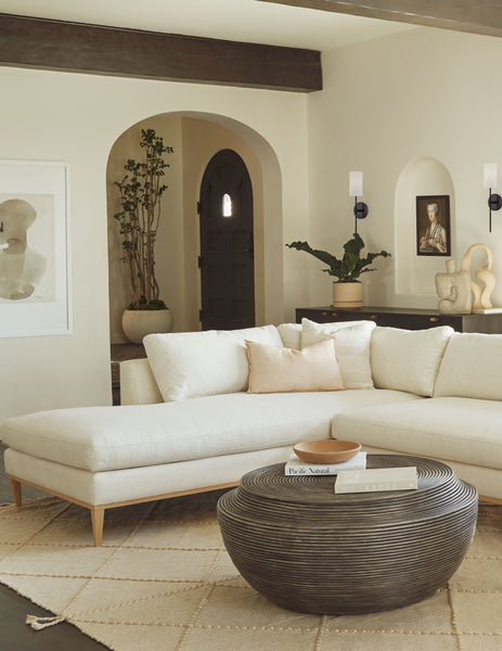 | The Sina gray washed handcrafted paper mache vase sits in the corner of a living room with a white sectional sofa, a round wooden coffee table, and a natural textured rug