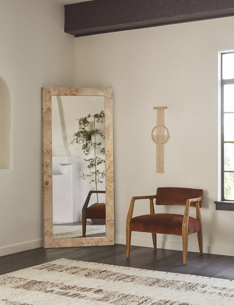 | Bree Burl Wood Rectangular Floor Mirror sits in the corner of a room with a cognac velvet accent chair and a natural wall hanging