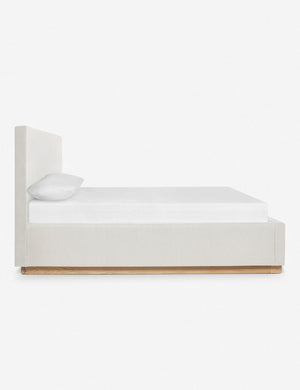 A side view of the Lockwood white velvet-upholstered bed with a white oak base.