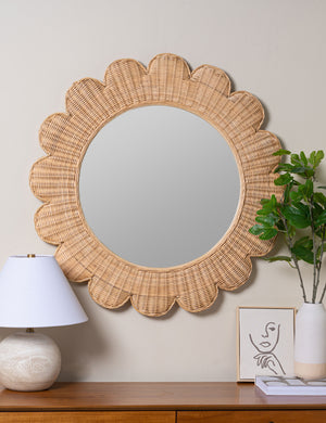 Asha round scalloped wicker framed mirror hanging on wall above a console table