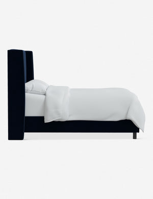 Side view of Adara navy velvet upholstered bed.