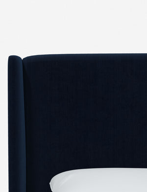 Close-up of the subtle winged headboard and trim lines on the Adara navy velvet upholstered bed.