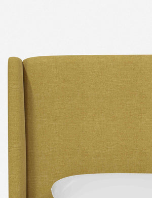 Close-up of the subtle winged headboard and trim lines on the Adara yellow linen upholstered bed.