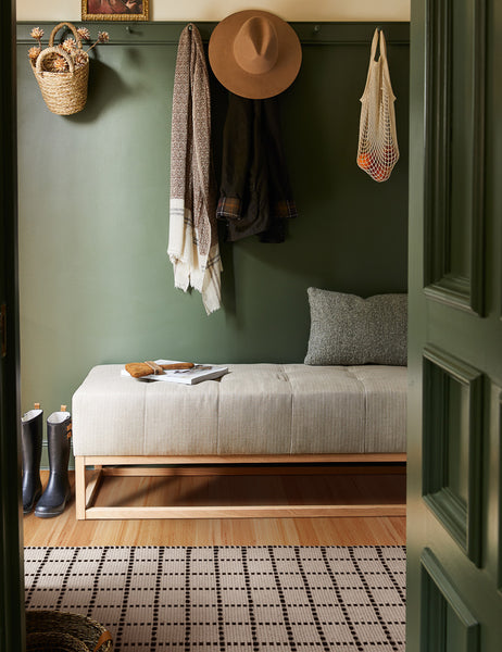 #size::1-9--x-2-10- #size::2--x-5- | The Sebou natural and black dotted machine washable mat lays in a green entry way with a gray linen cushioned bench