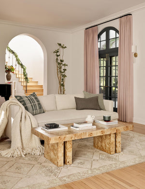 Natural Velvet Belmont Sofa sits in a living room behind a burl wood coffee table and atop a neutral-toned patterned rug