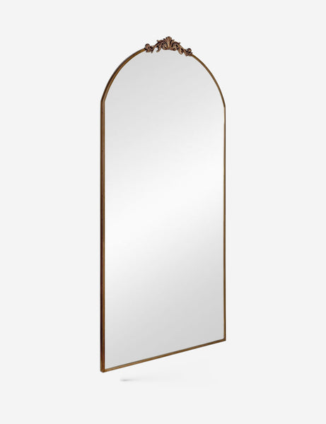 #color::gold | Angled view of the Tulca gold curved standing mirror with flat bottom edge and traditional scroll detailing.