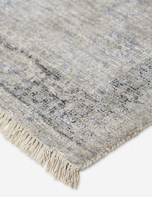 Close-up of the natural fiber fabric and fringed ends on the corner of the Ismenia distressed slate-toned persian rug