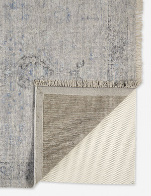 Close-up of the corner of the Ismenia distressed slate-toned persian rug with fringed ends with the bottom folded over