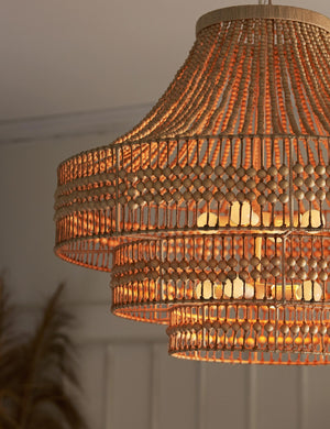 The Tulane open-woven wooden chandelier by Arteriors in a dark room with its lights on
